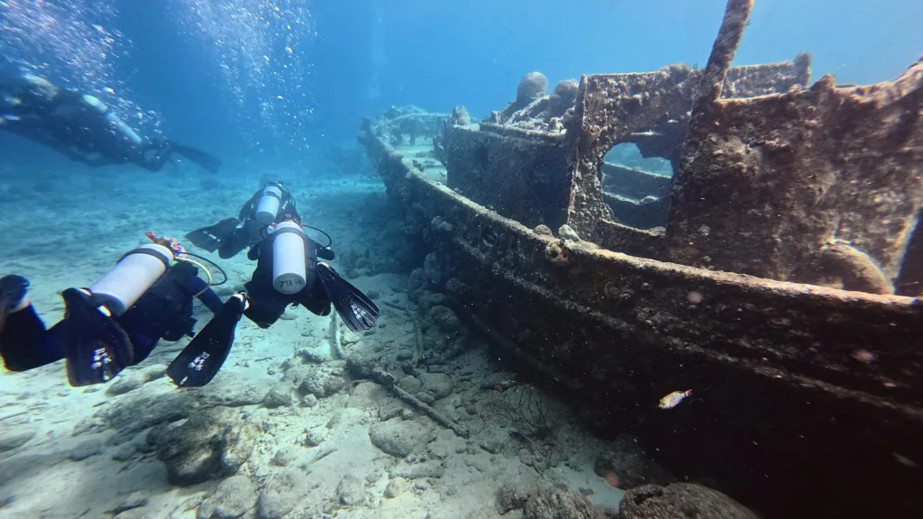 Buzos recorriendo un naufragio en el fondo de arena en Curaçao