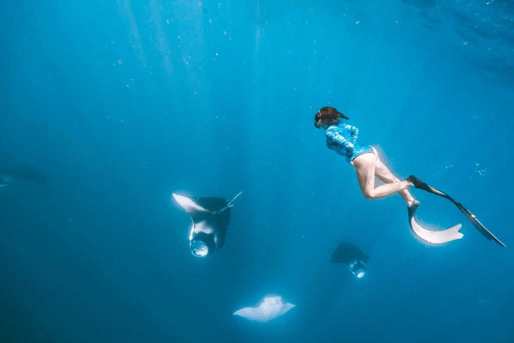 Dalina nadando bajo el agua entre mantas