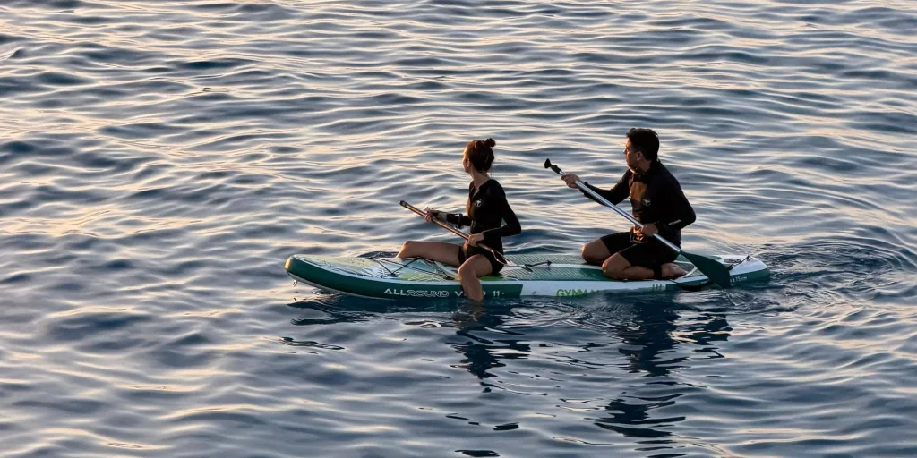 Mile y Joe remando juntos en una tabla de stand up paddle al atardecer